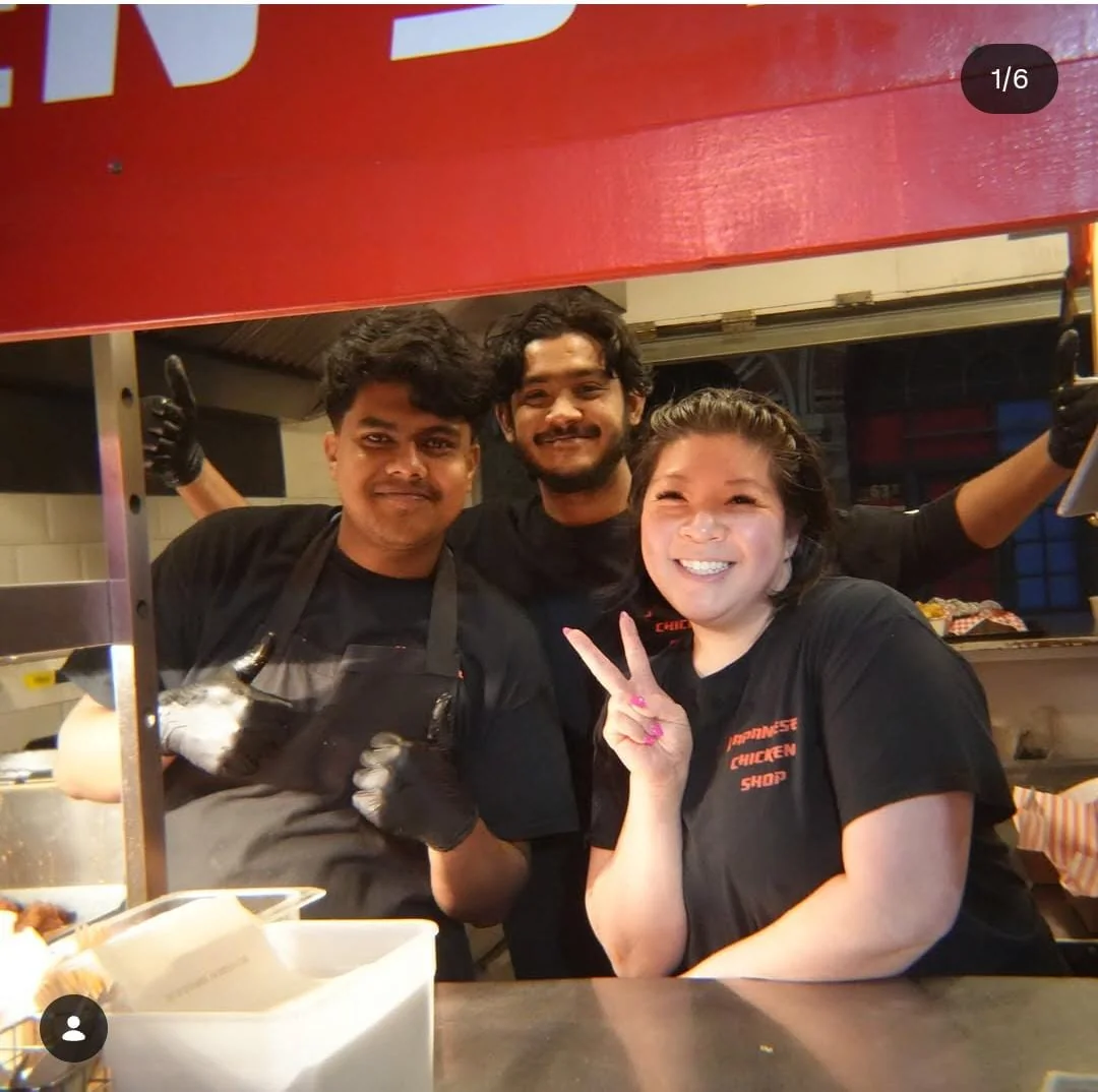 Three Japanese Chicken Shop team members smiling together at their red food stall