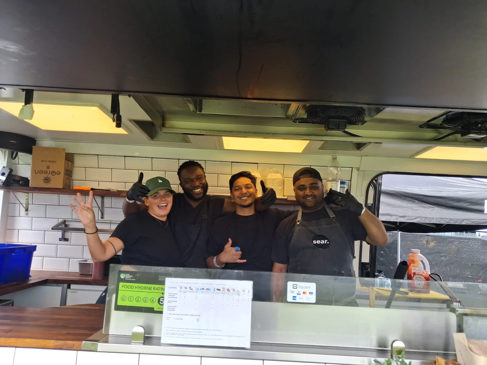 Four sear team members smiling together inside their food truck