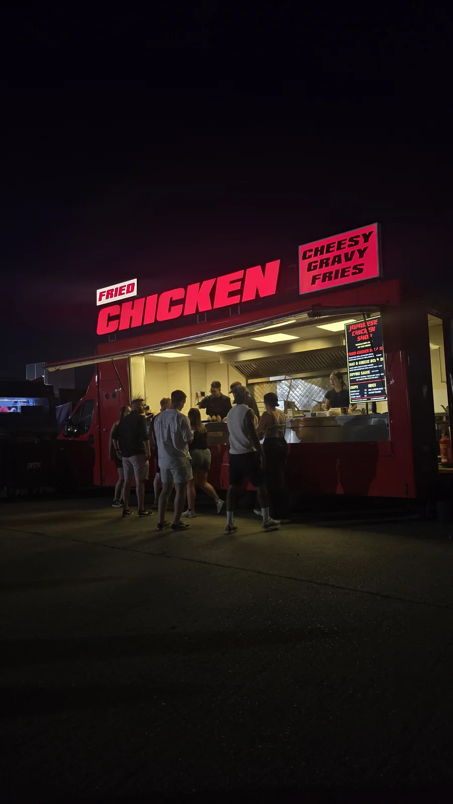 Customers at the illuminated Big Red food truck at night
