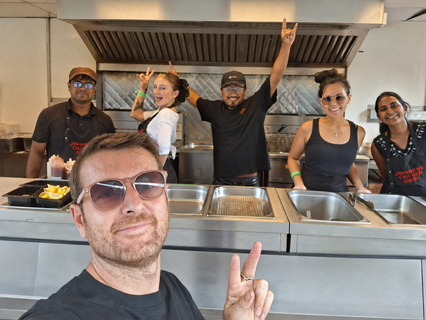 Japanese Chicken Shop team in their kitchen, with a team member celebrating with his arms raised
